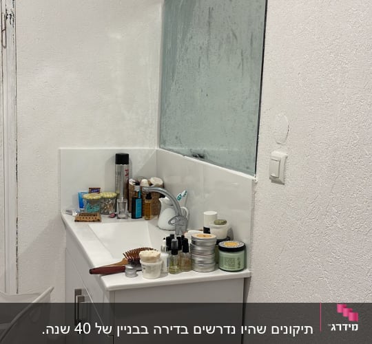 כיור אמבטיה עם מראה גדולה, מוצרי טיפוח ומברשות שיער